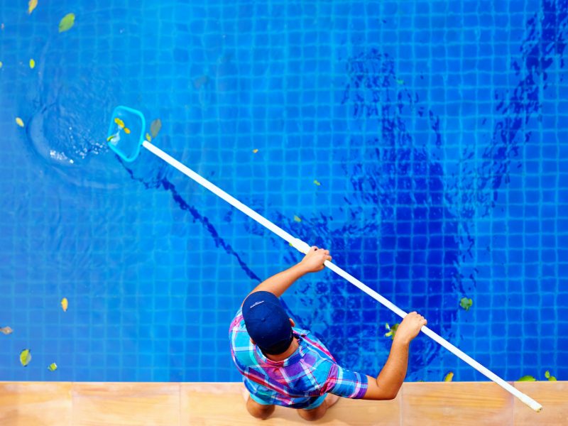 A person cleaning the swimming pool